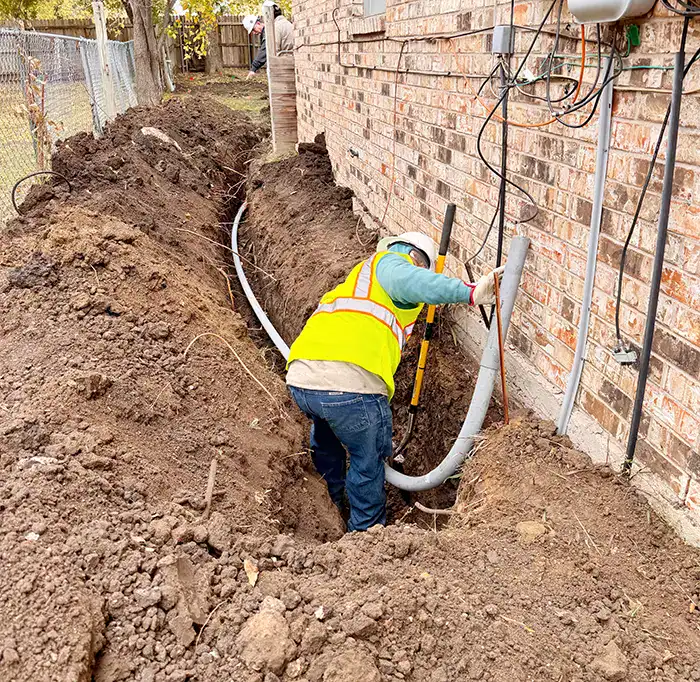 Construction crew performing trench excavation and pipe installation in Fort Worth, Dallas area, with heavy machinery and safety equipment on site.